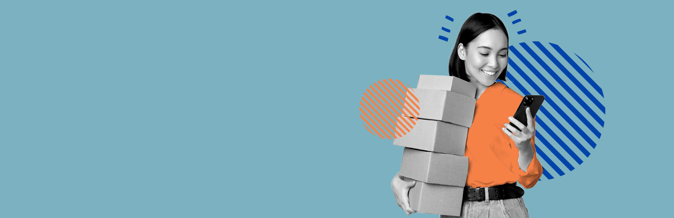 Mujer joven cargando cajas en una mano y mirando su celular en la otra mano