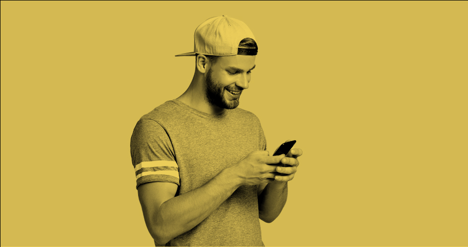 hombre joven con gorra sosteniendo y mirando fijamente su celular