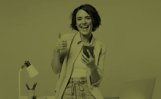 Mujer sentada en escritorio mientras levanta su pulgar con emoción