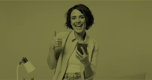 Mujer sentada en escritorio mientras levanta su pulgar con emoción